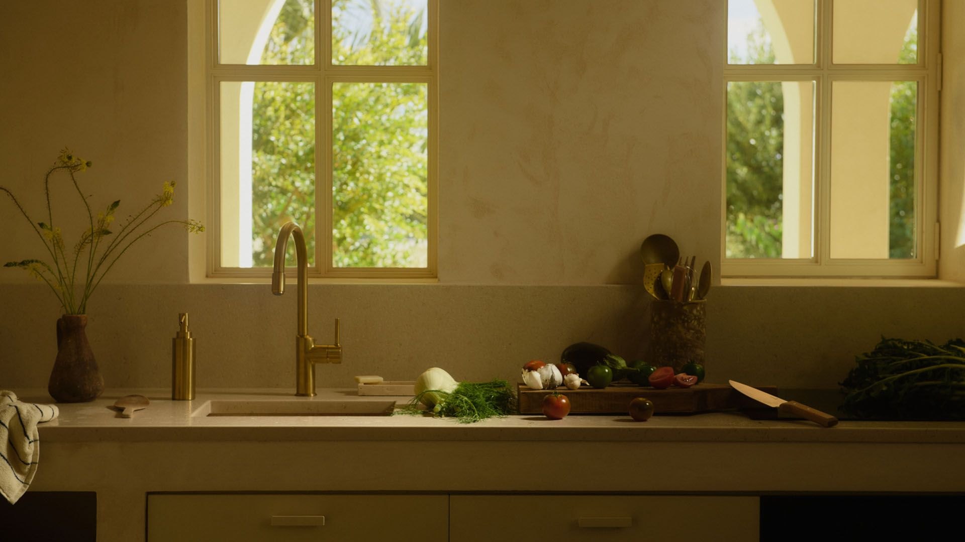 Rubinetto da cucina in ottone davanti a finestre ad arco, in un ambiente mediterraneo