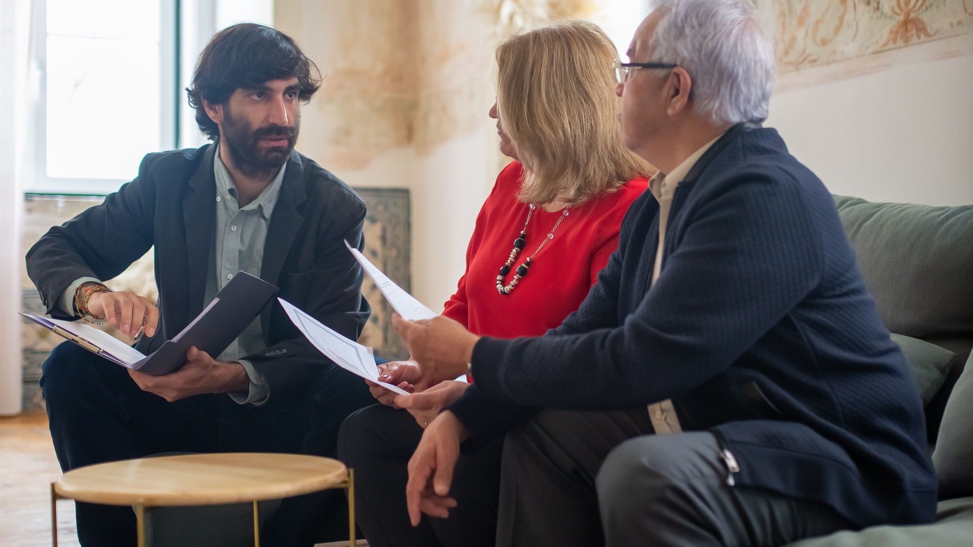 Consulente e coppia di clienti che esaminano insieme dei documenti in un salotto luminoso