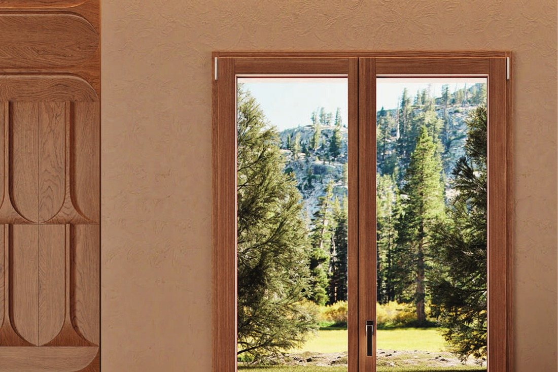 Porta-finestra in legno Fossati Nova affacciata su un bosco di montagna