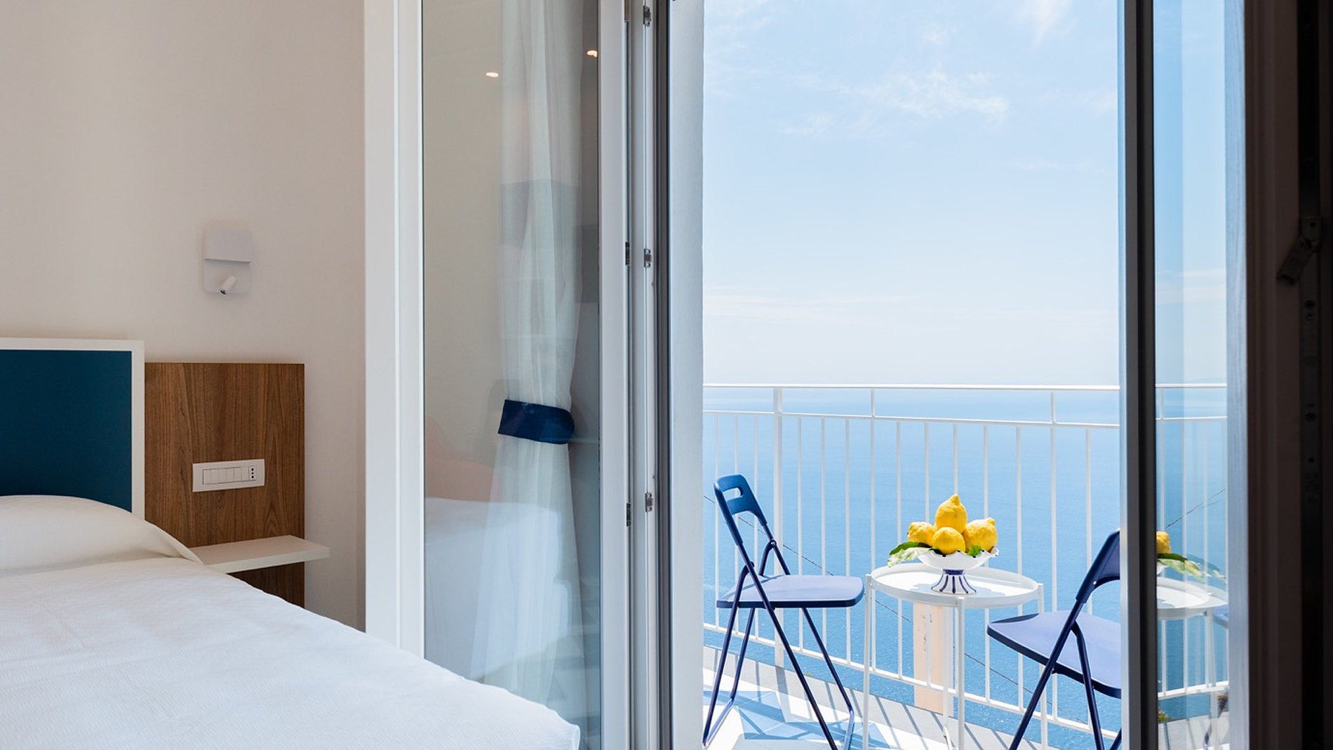 Porta-finestra a più ante completamente aperta su un balcone affacciato sul mare