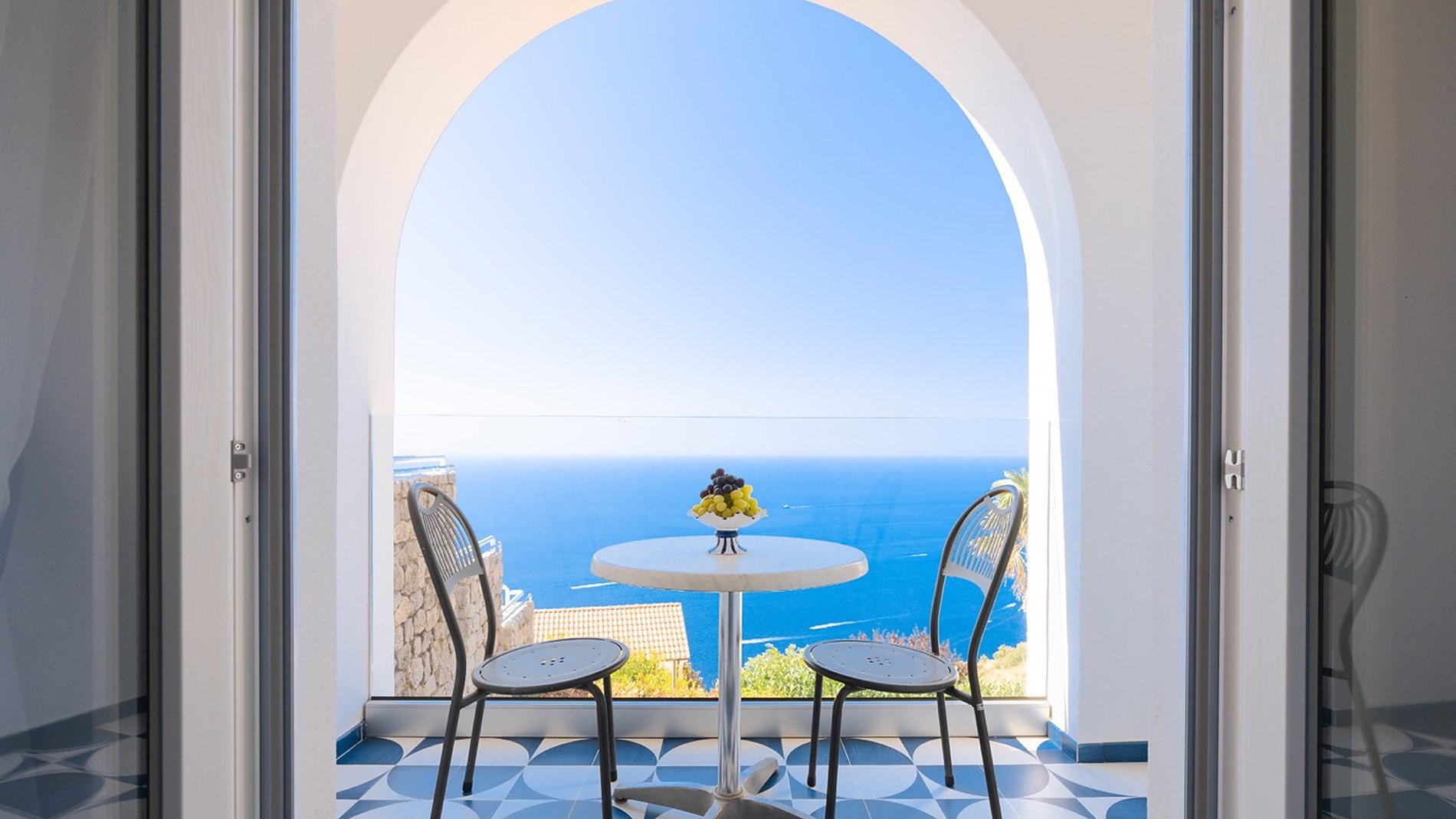 Porta-finestra a due ante spalancata su una terrazza con vista sul mare