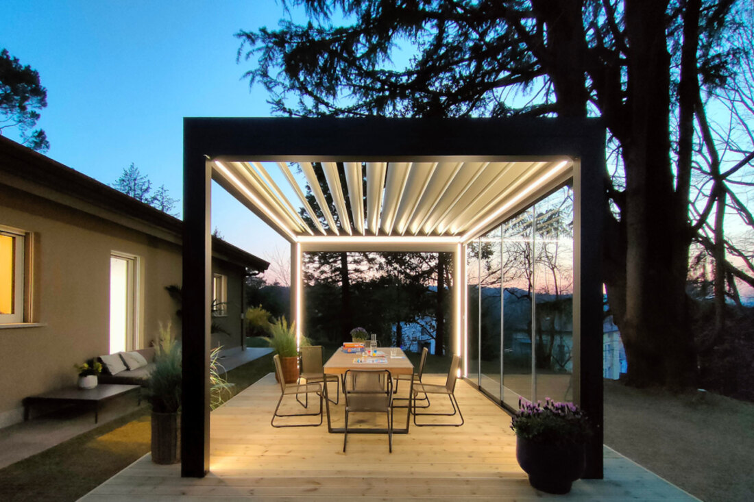 Pergola bioclimatica antracite illuminata dal LED integrato nella struttura, di sera