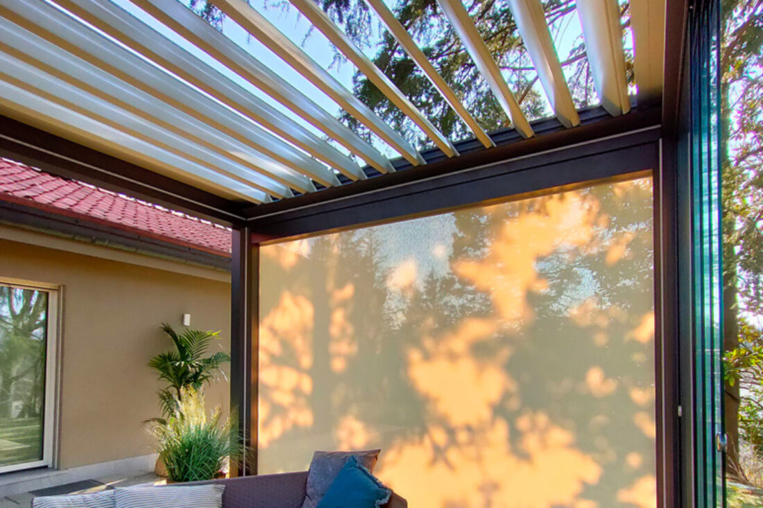 Chiusura verticale a telo abbassata su un lato della pergola, sotto il tetto a lame aperte