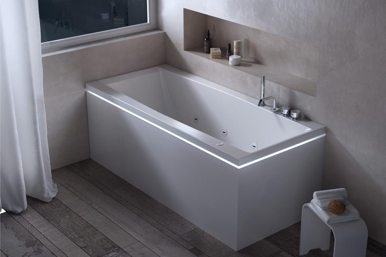 Vasca installata a filo parete in un bagno con nicchia e tende chiare